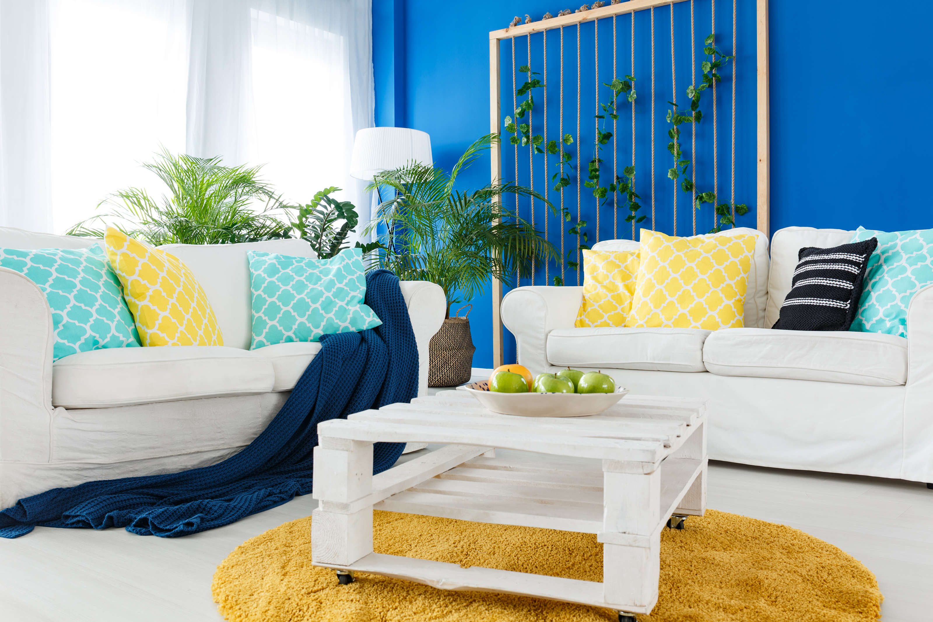 Up-to-date decor of spacious living room with colorful walls, white furniture, and bright accents.