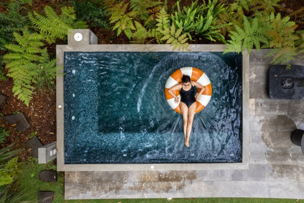 Woman relaxing on an inflatable ring in a modern, square plunge pool.