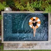 Woman relaxing on an inflatable ring in a modern, square plunge pool.