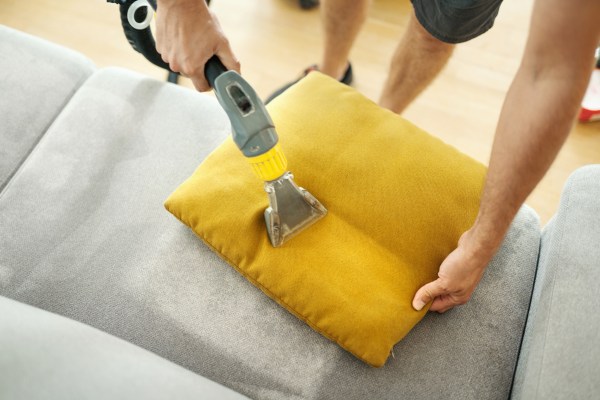 View from above of someone performing a deep cleaning of a of sofa cushions