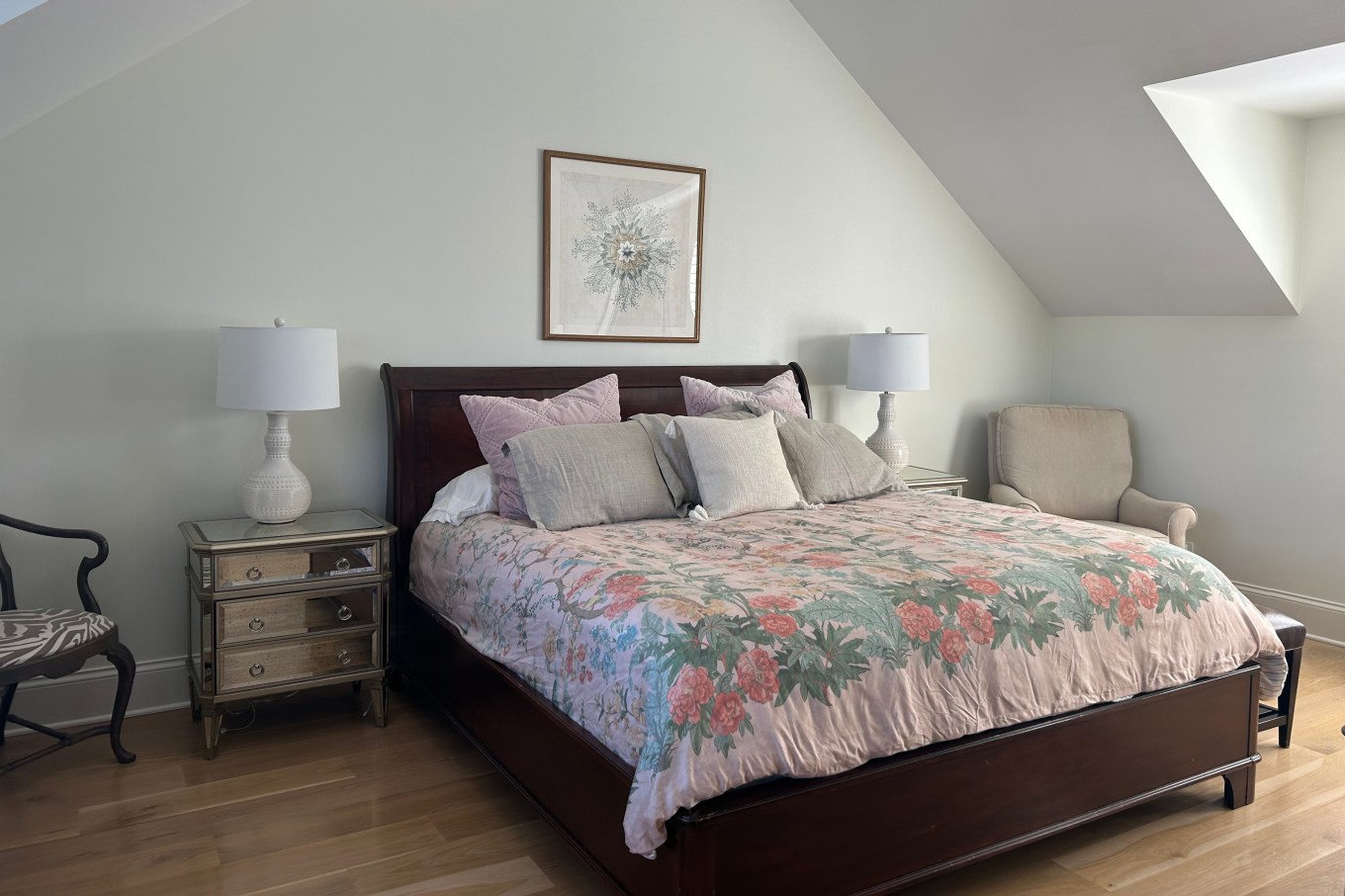 A beautiful, made bed with floral sheets in a room with white walls.