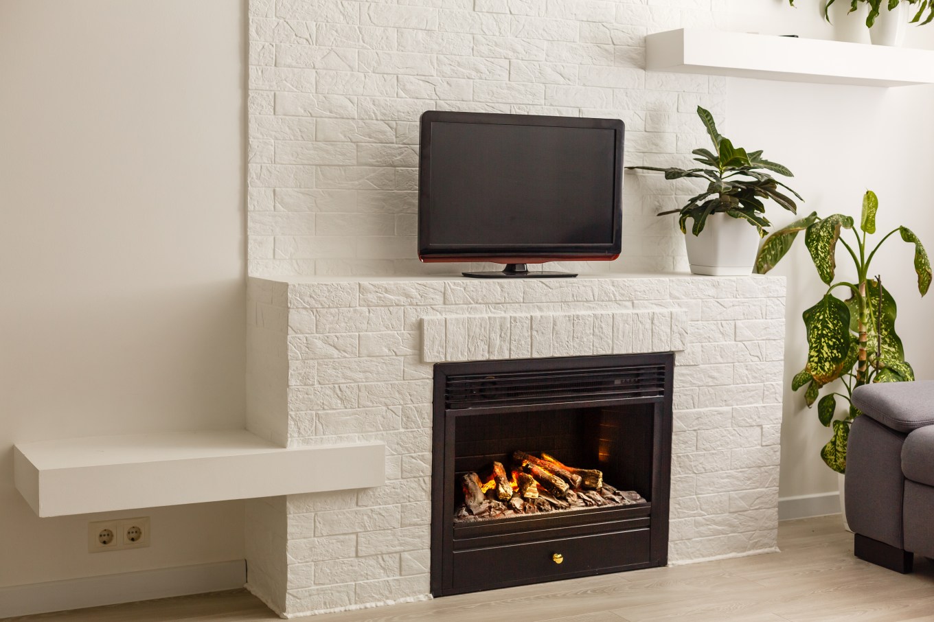 A modern fireplace in a contemporary, white-walled room with a TV above the fireplace.
