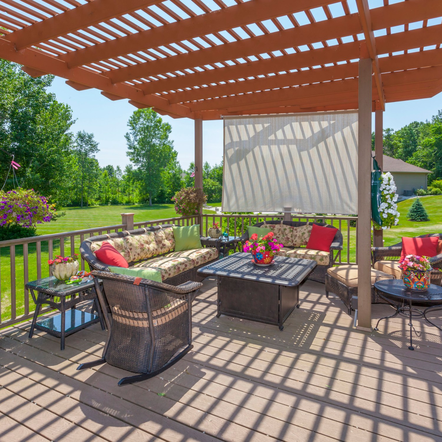 An inviting backyard deck with chairs, a table and a pergola to cover it.