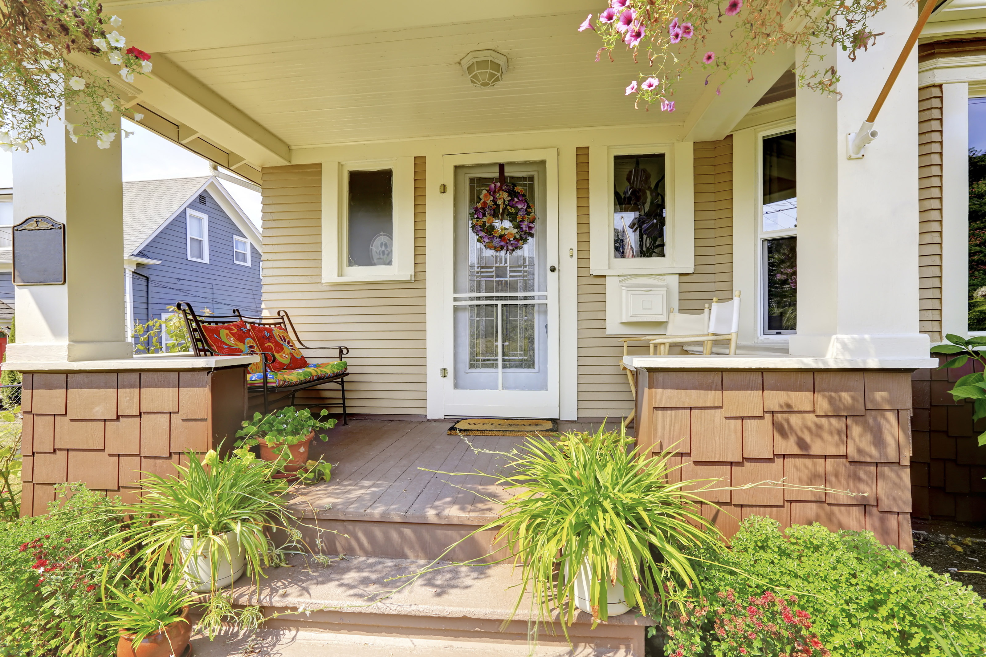 American craftsman house exterior. Cozy covered porch with white columns and lots of flowers in the front.