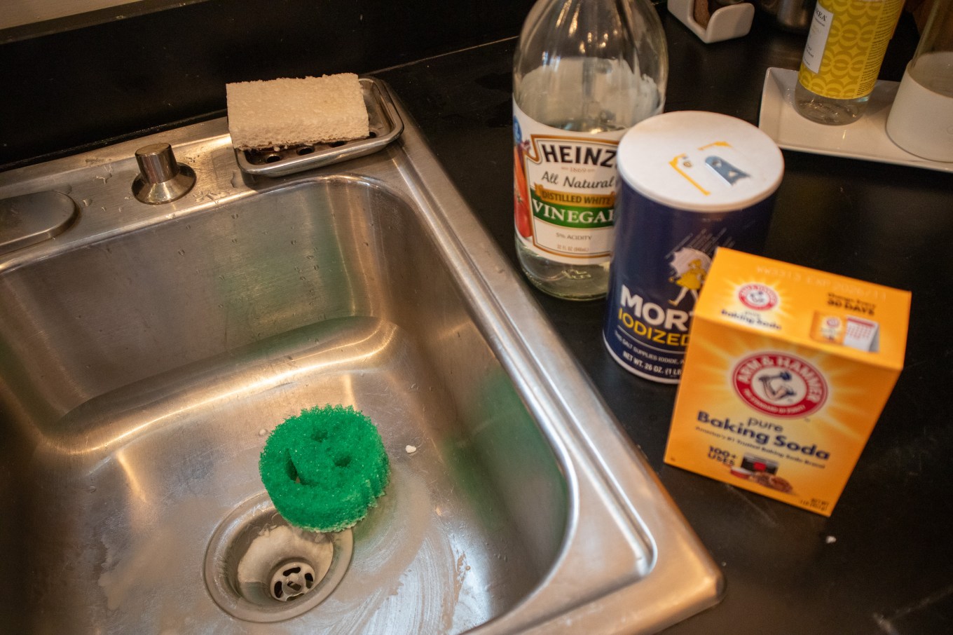 Baking soda, vinegar, and salt by a sink to be used for cleaning.