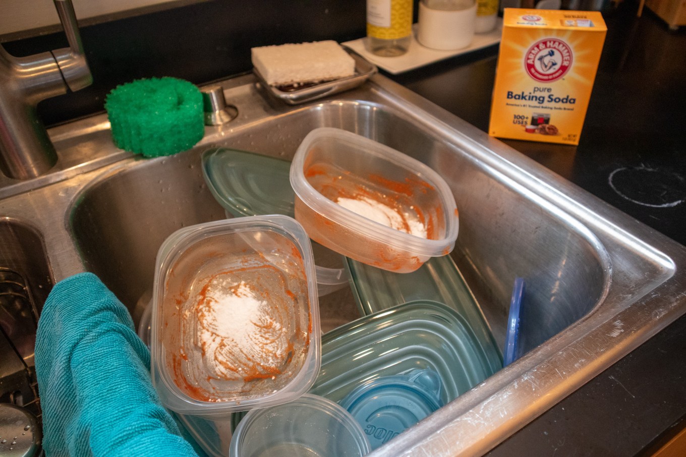 Baking soda being used in Tupperware containers to clean them.
