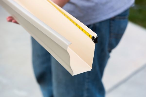 Someone measuring a seamless gutter made of aluminum.