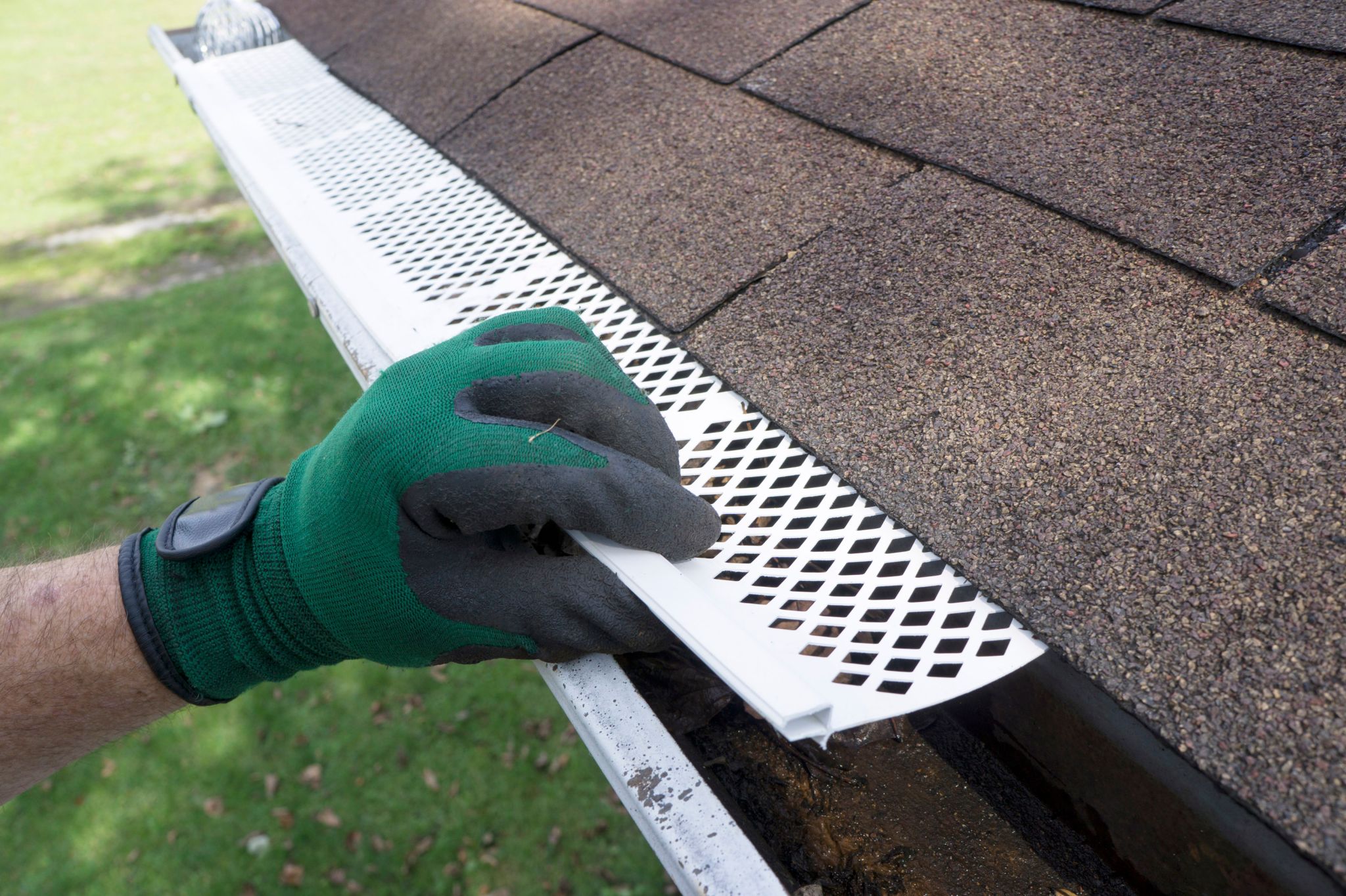 Someone installing plastic gutter guards to get them to fit into place.