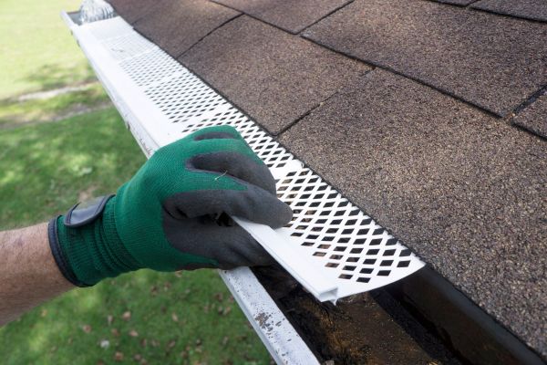 Someone installing plastic gutter guards to get them to fit into place.
