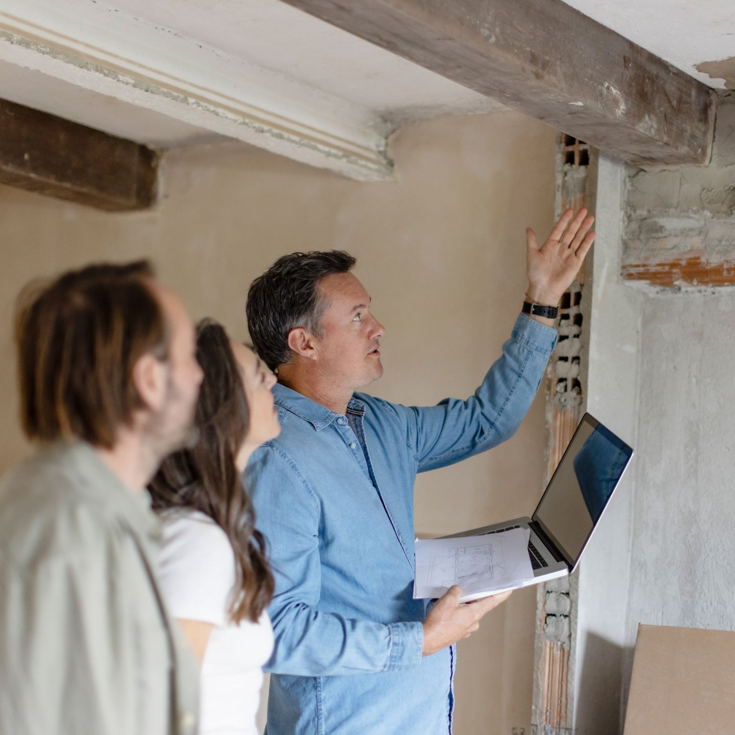 Home inspector and home owners discussing problems in an unfinished basement.