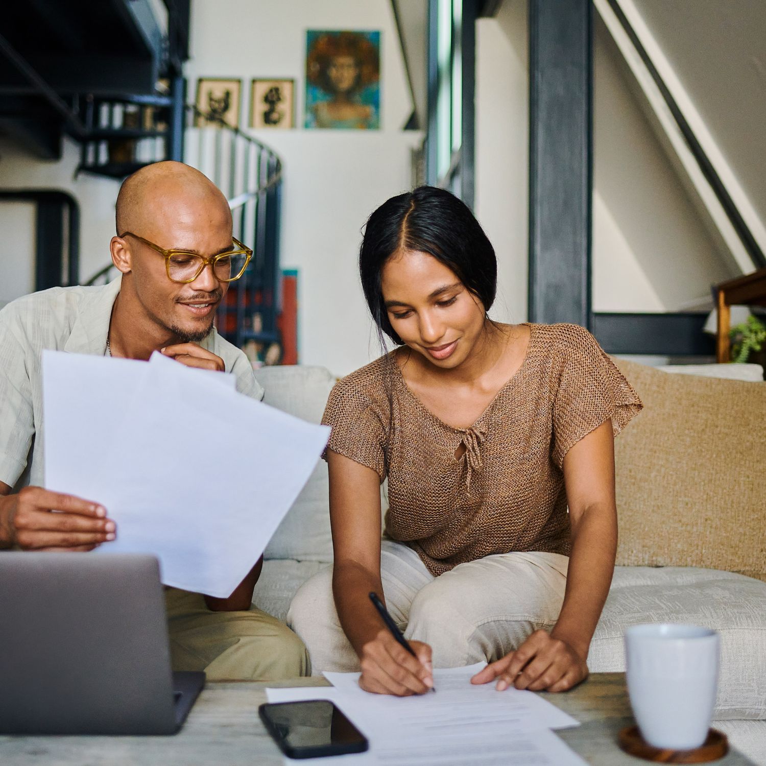A young couple is sitting in their living room, going over homeowner's insurance documents after a home inspection.