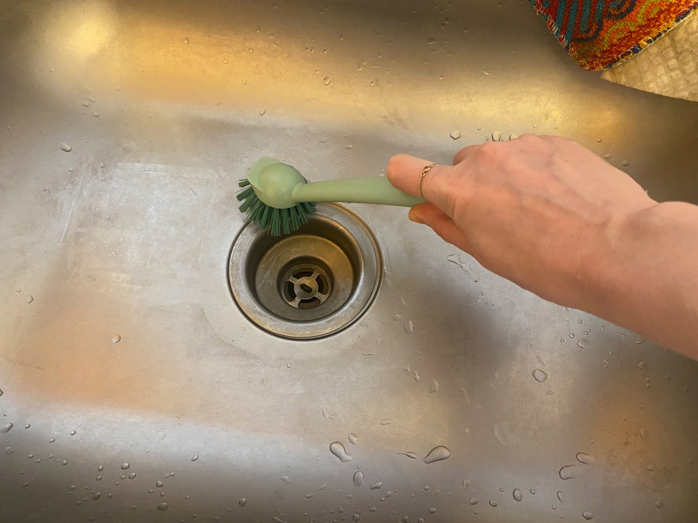 The drain of a kitchen sink being scrubbed.