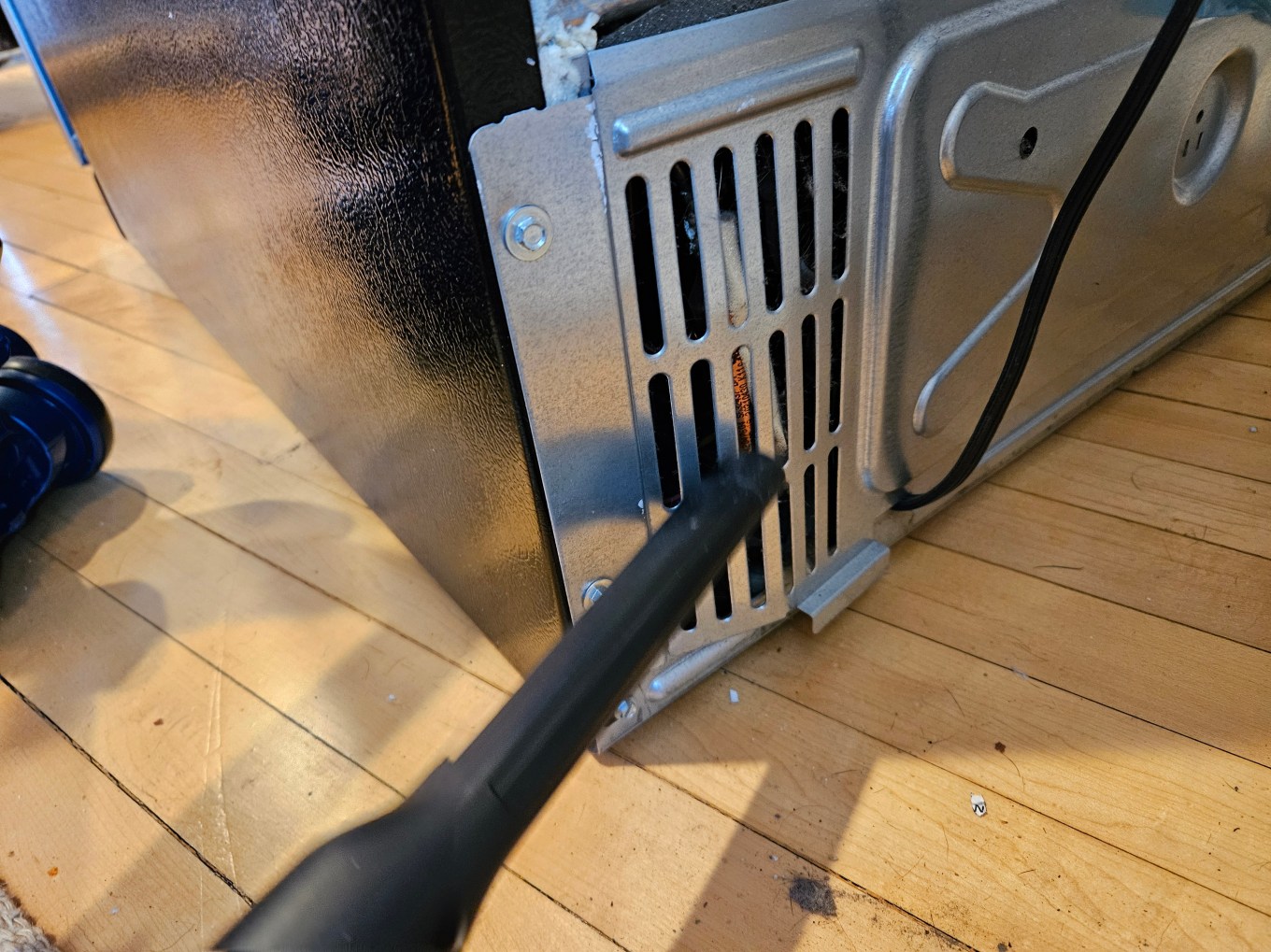 The coils of a fridge being vacuumed.