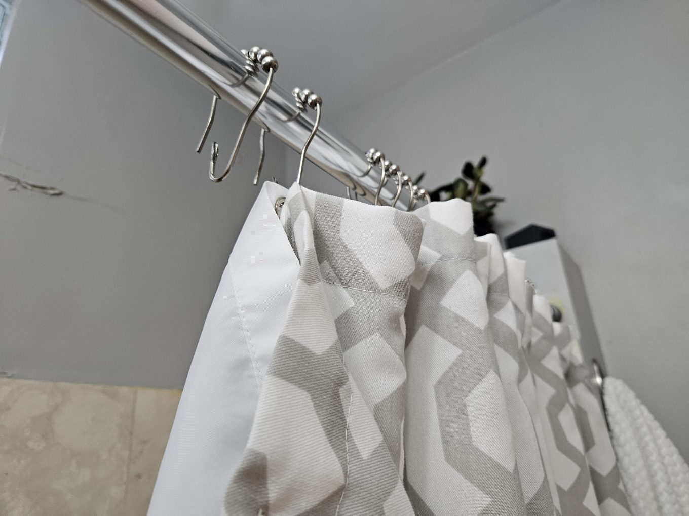 A shower curtain being removed for cleaning.