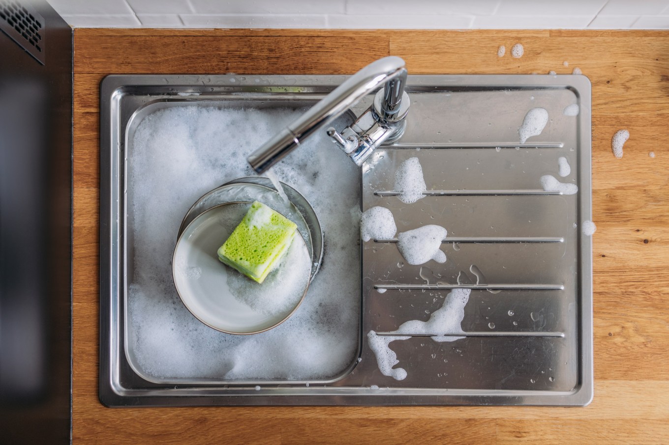 Overhead shot of sponge in a soapy sink. Things you need to clean in the kitchen and bathroom.