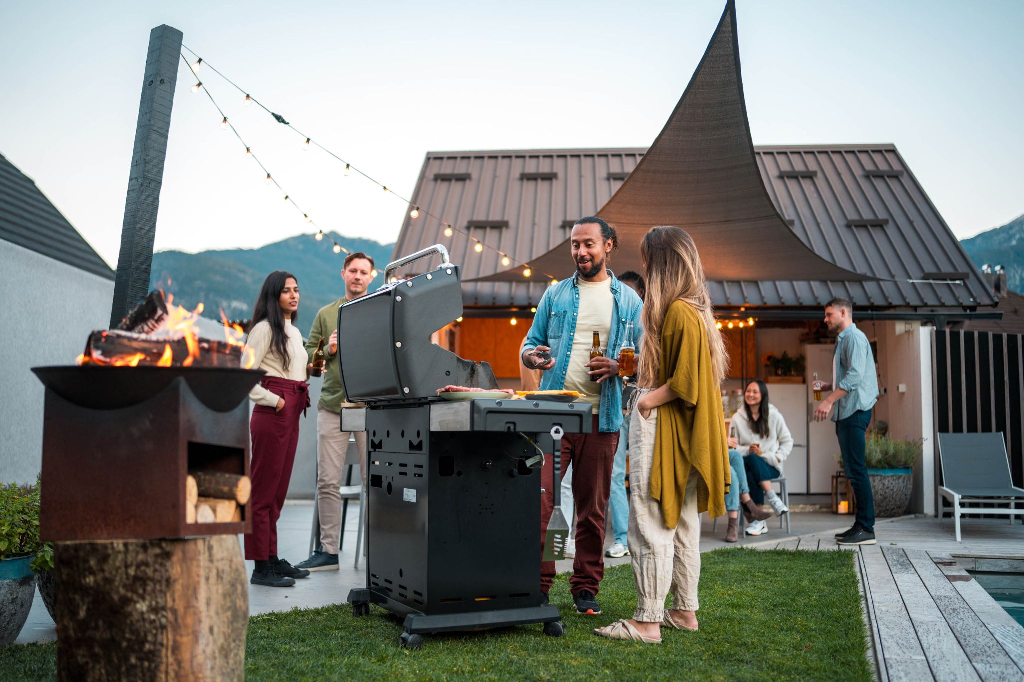 A beautiful backyard setting with a group of people enjoying an outdoor barbecue, exemplifying the benefits of maintaining your outdoor space this Summer.