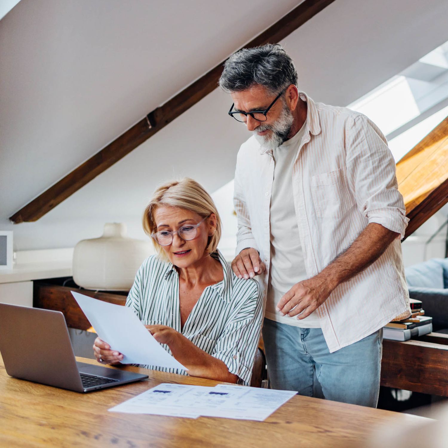 Senior couple reviewing discrepancies financial documents at home office.