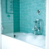 A classic bathtub with tiling on the wall showing what might be replacing showers.