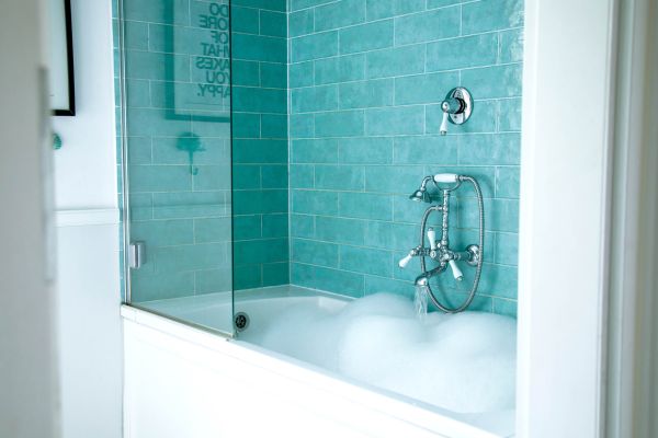 A classic bathtub with tiling on the wall showing what might be replacing showers.