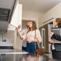 A female real estate agent showing a house with updated features to a young couple.
