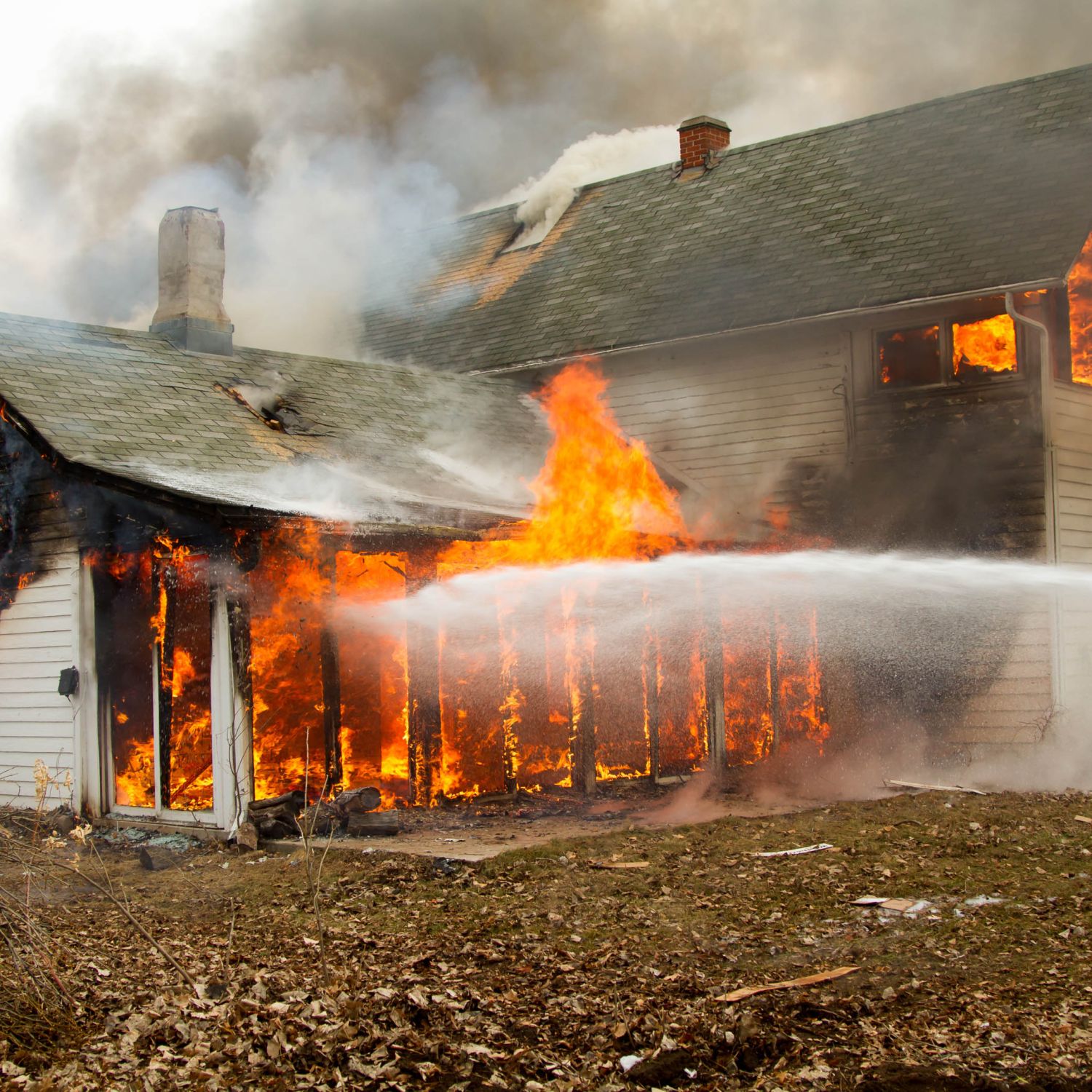 A burning building with a stream of water hitting it, highlighting fire safety.
