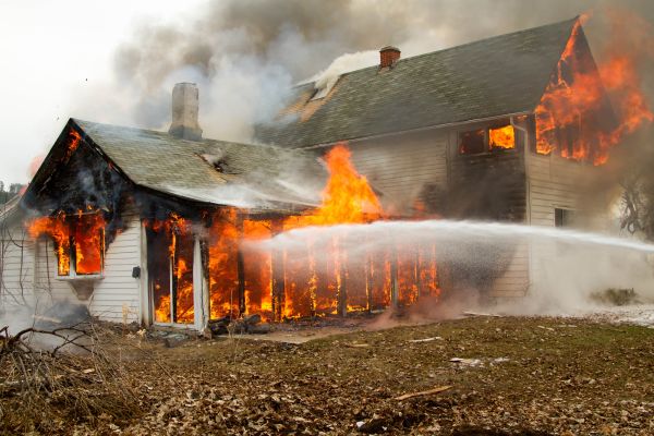 A burning building with a stream of water hitting it, highlighting fire safety.