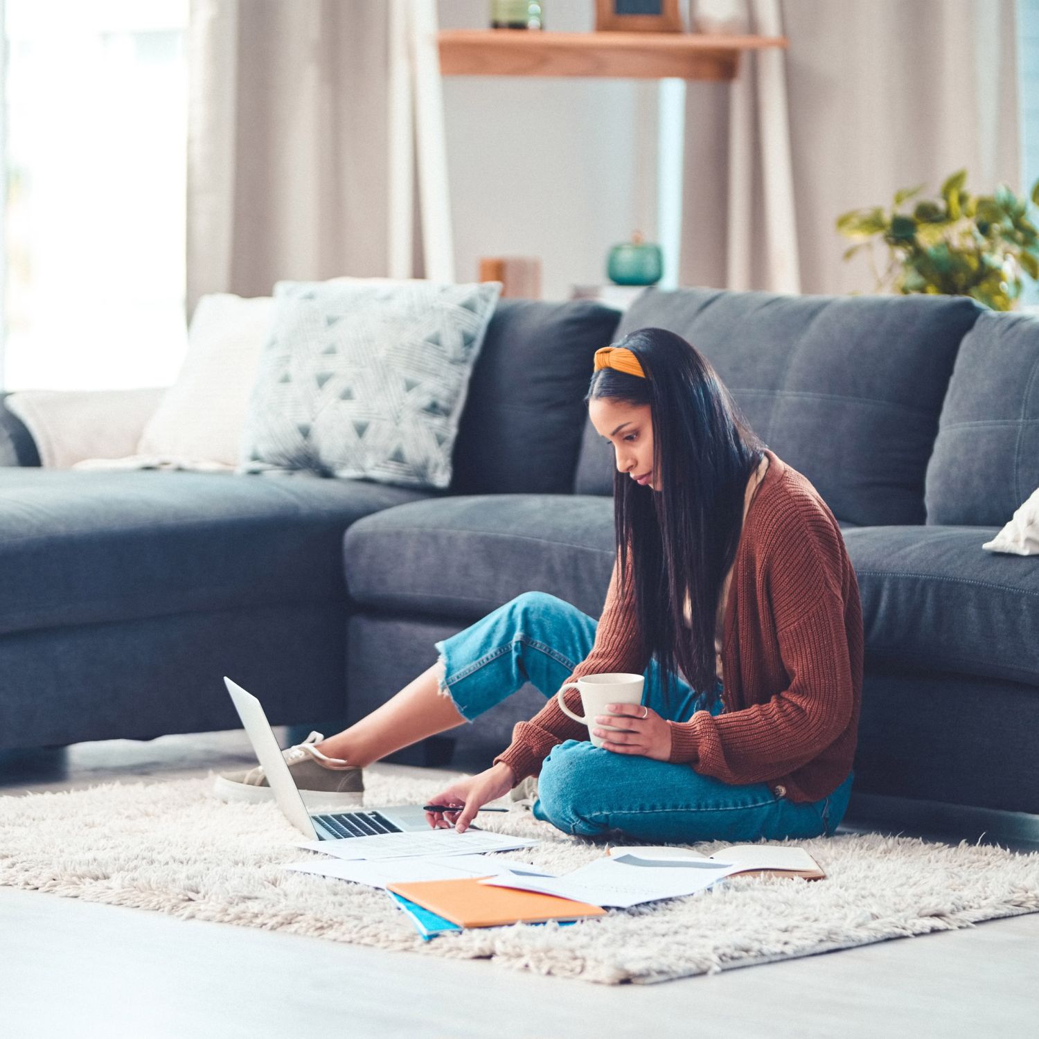 Shot of a young woman going through paperwork in the living room at home