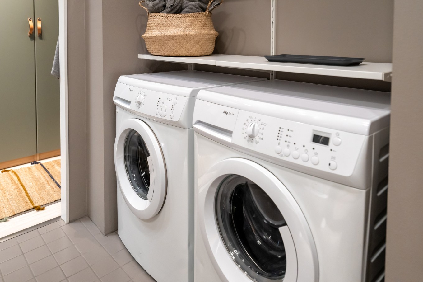 White front loading laundry machine installed in the laundry room.