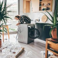 A man installing a new washing machine being careful to follow all instructions.