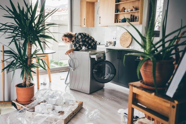 A man installing a new washing machine being careful to follow all instructions.