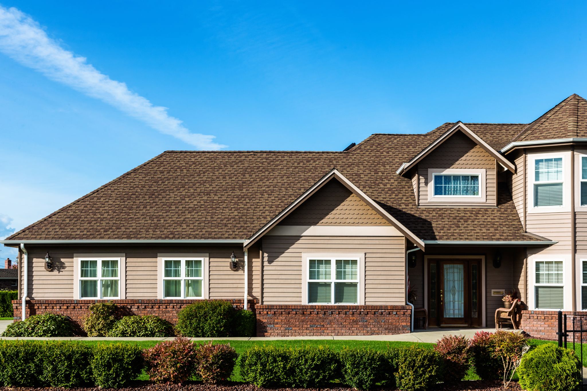 Partial image of a modern American home with focus on roof detail against blue sky.