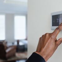 Close-up of a thermostat being set to decrease electric bills.