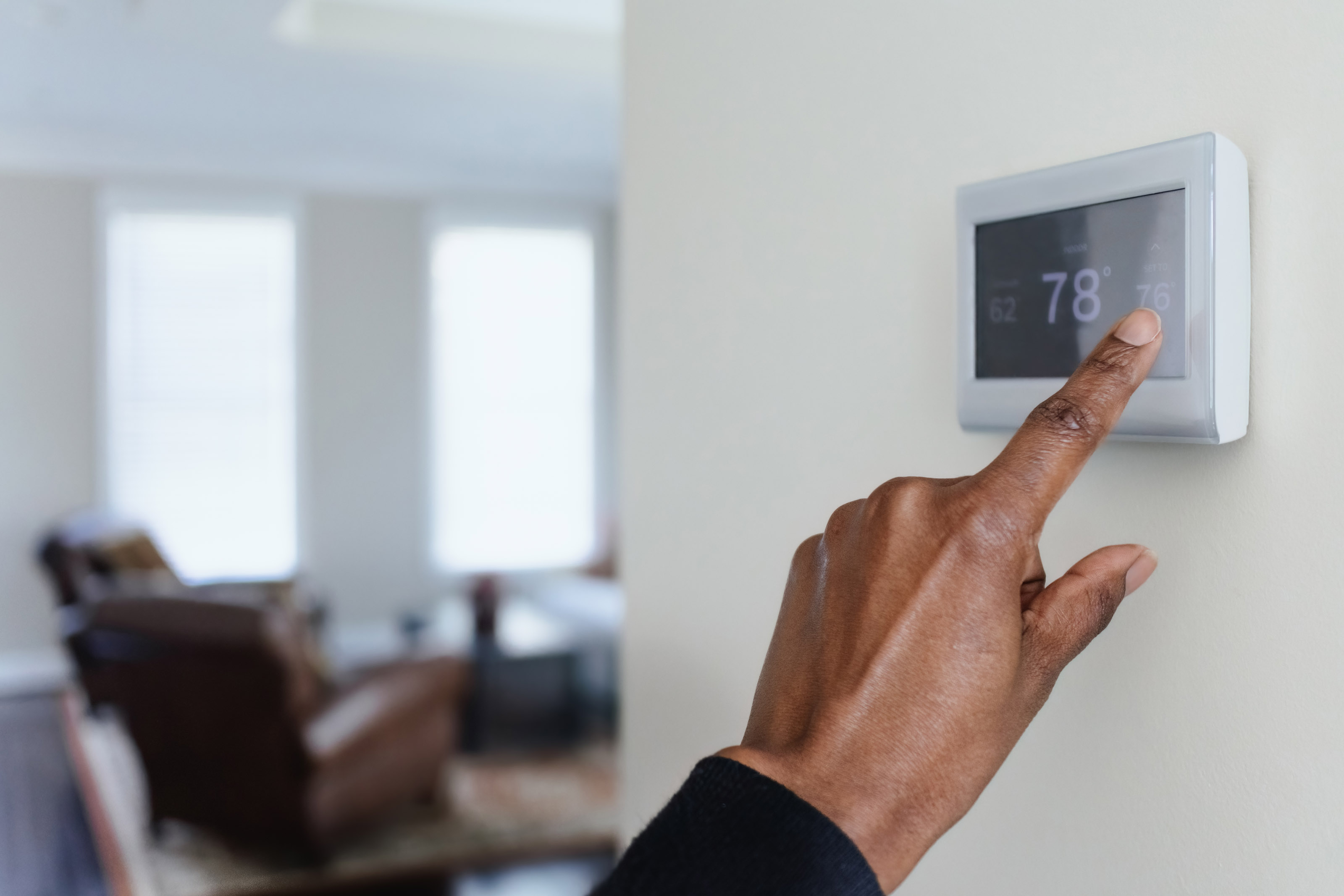 Close-up of a thermostat being set to decrease electric bills.