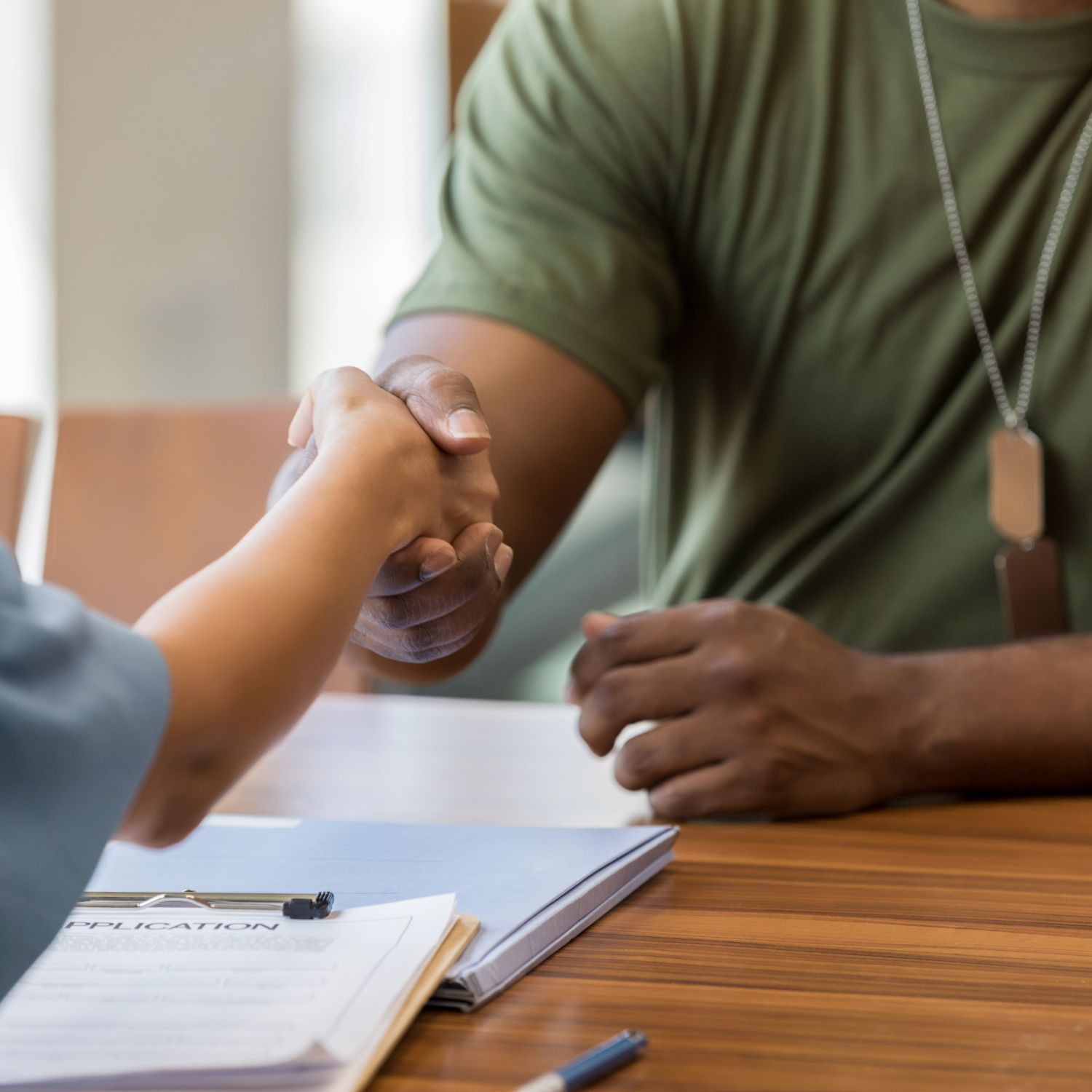 Unrecognizable male soldier shakes hand with a female bank officer. The soldier is applying for a loan.