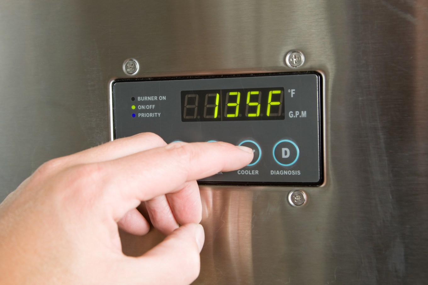 A hand turning down the temperature on a tankless water heater control panel.