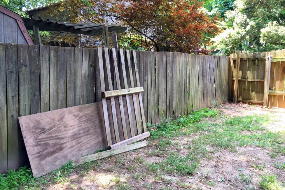 An old, mossy wood fence with patchy grass