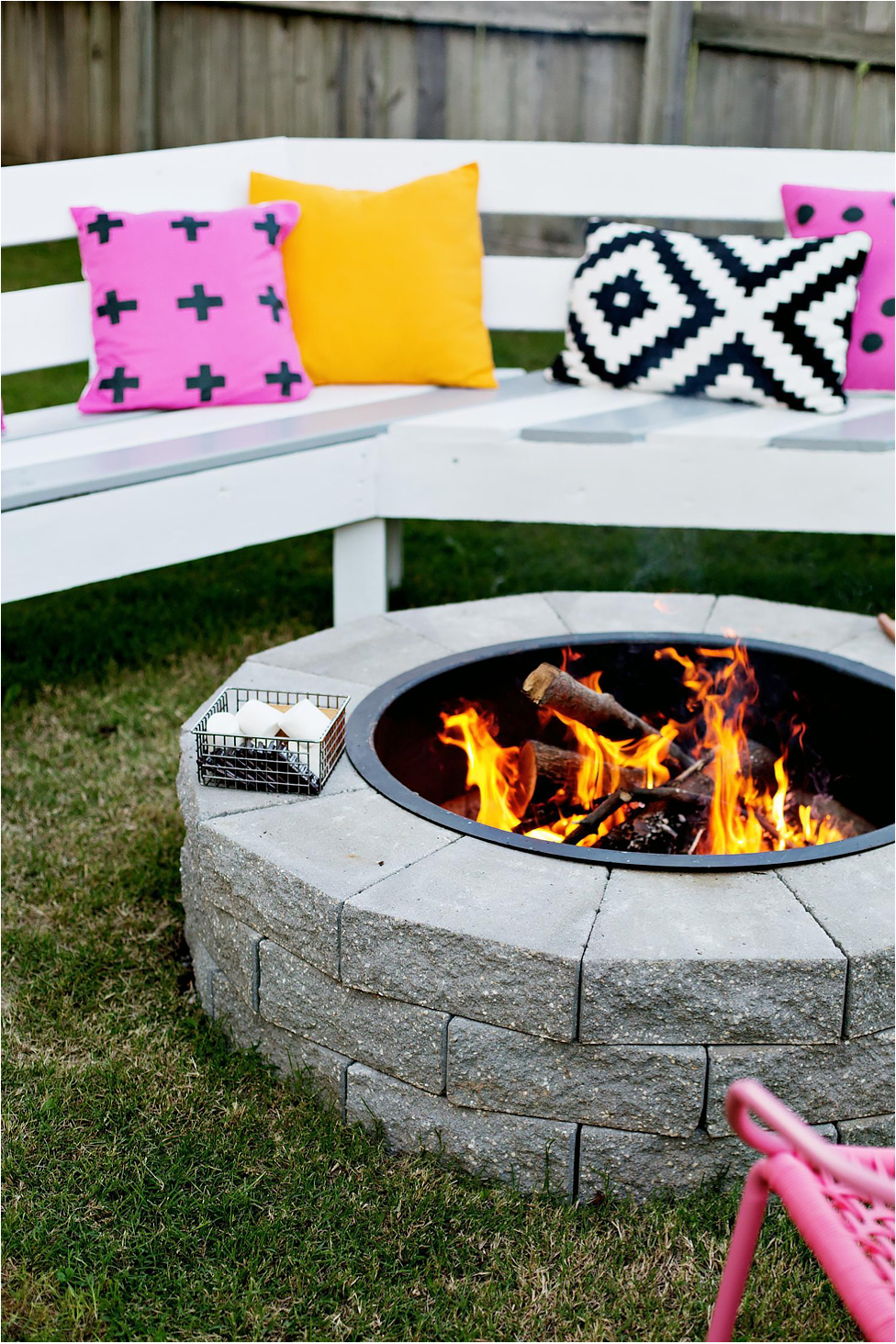 A firepit with a white bench with accent pillows