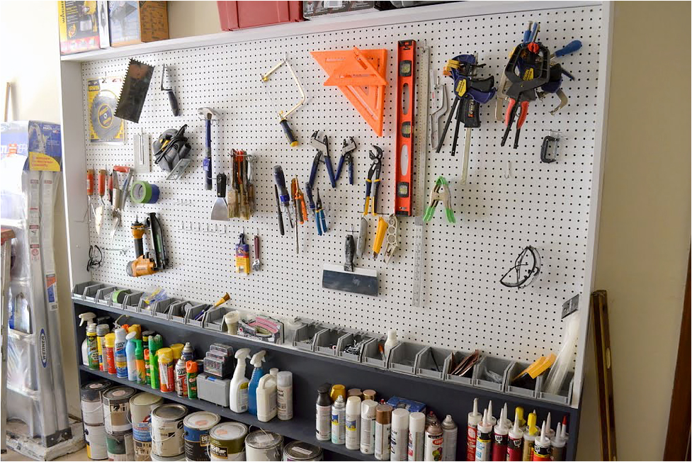 A white pegboard with tools in a garage
