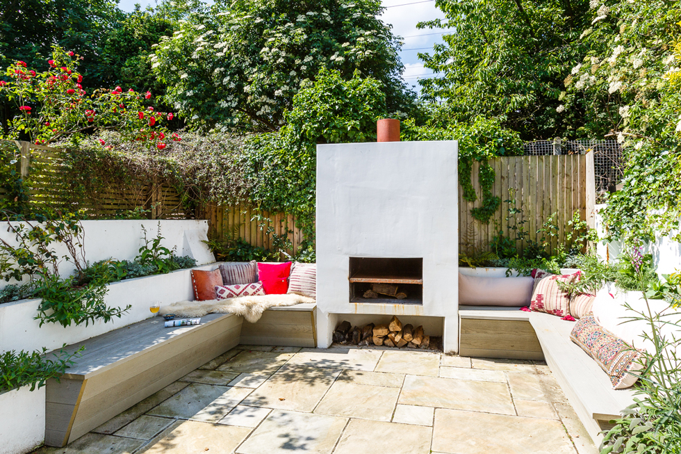 An outdoor fireplace with wood bench seating on a patio
