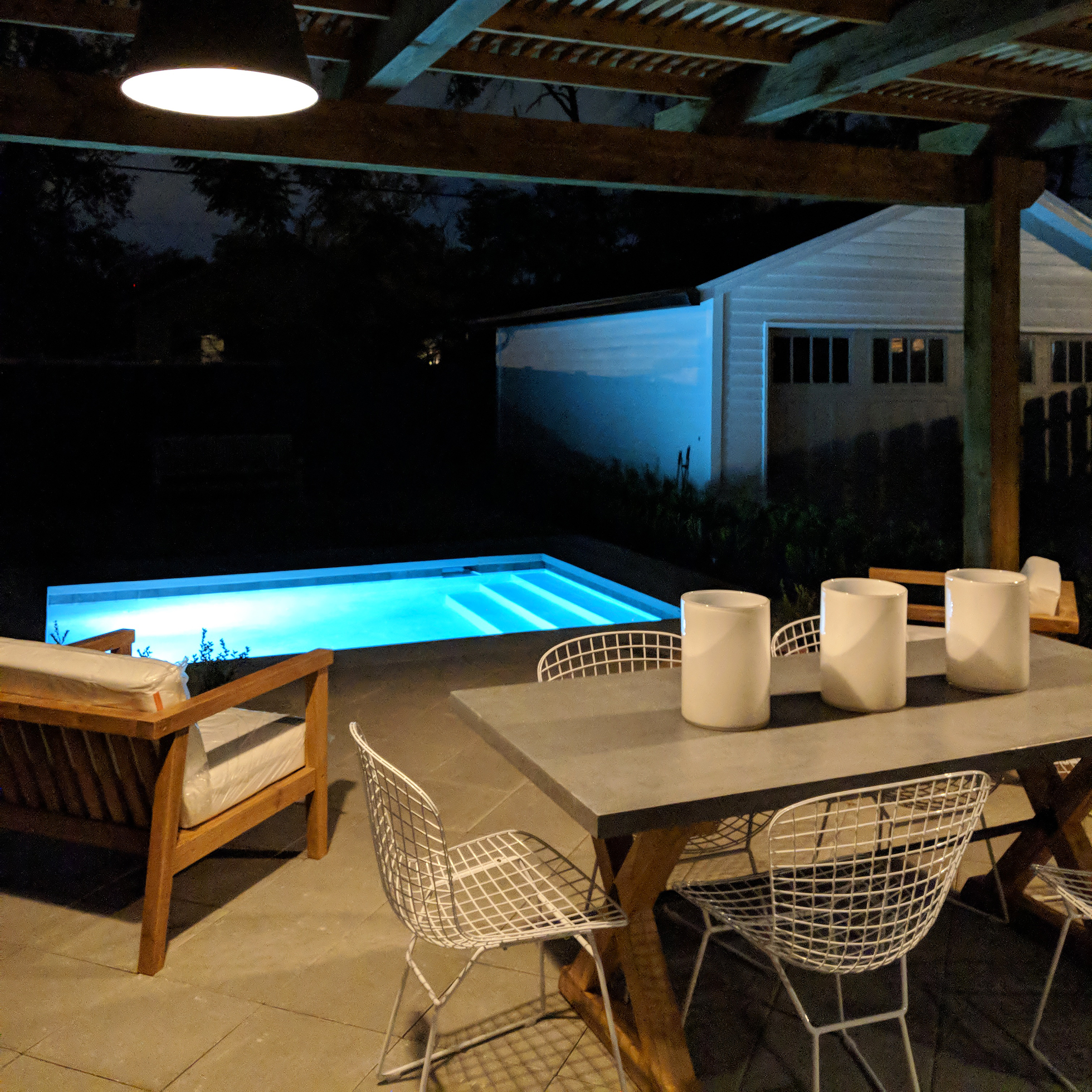 A backyard with pool and covered patio at night