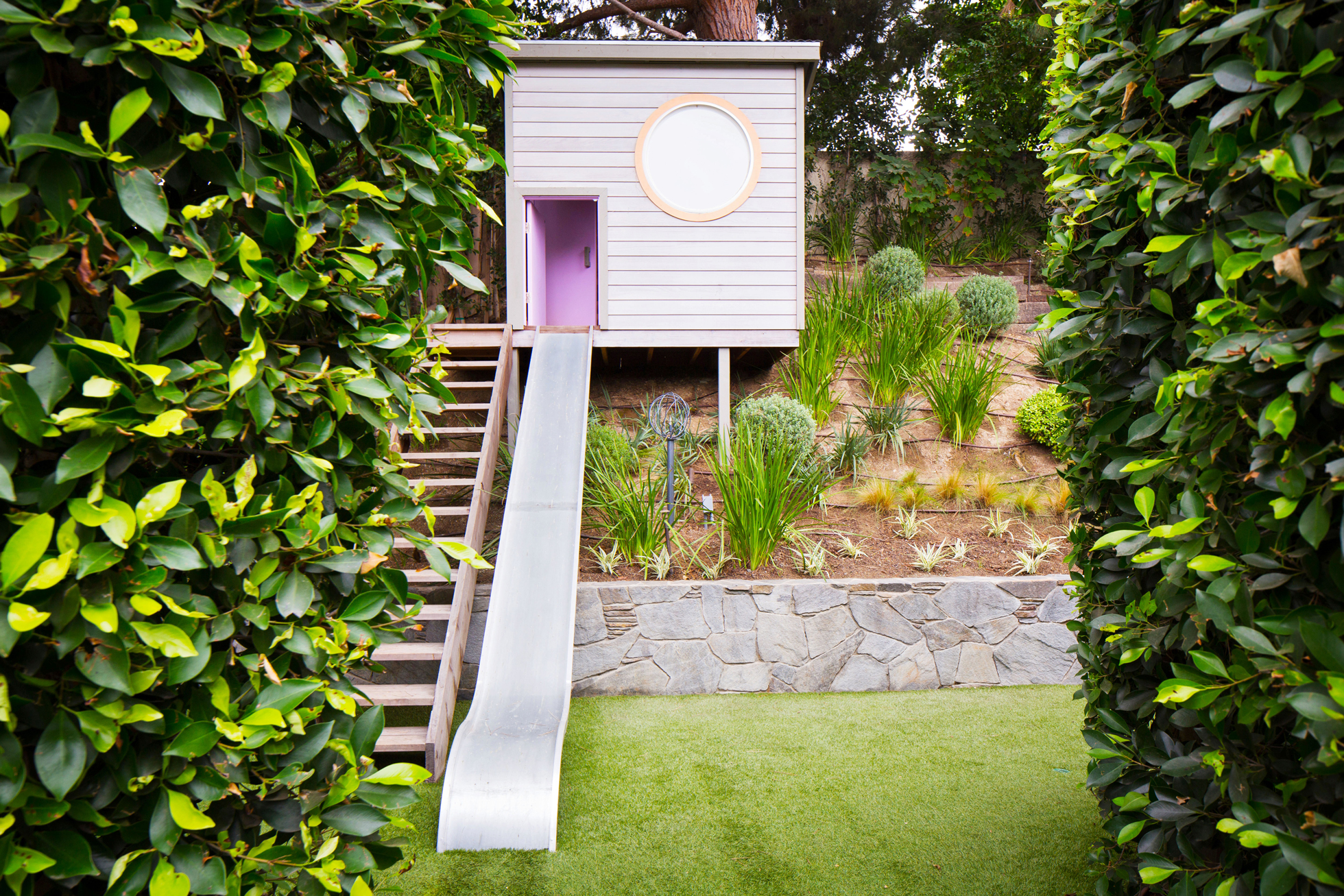 A modern treehouse with a purple slide