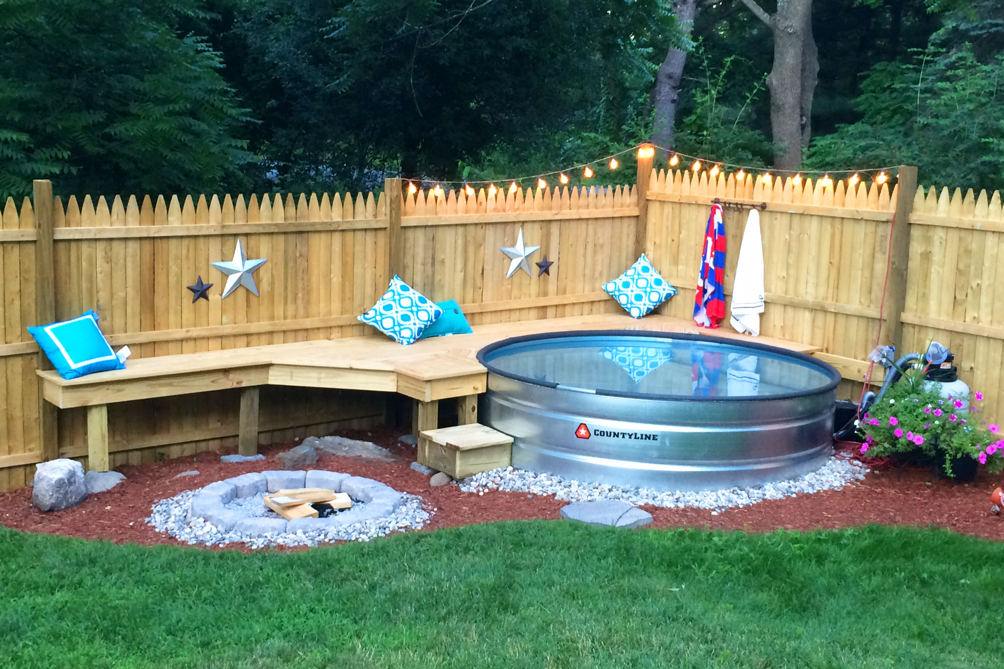A stock tank pool and a fire pit with seating in a backyard