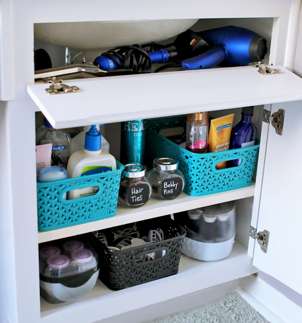Toiletries in baskets and jars under a bathroom sink