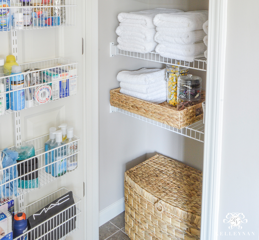 A linen closet filled with towels and a wire rack on door