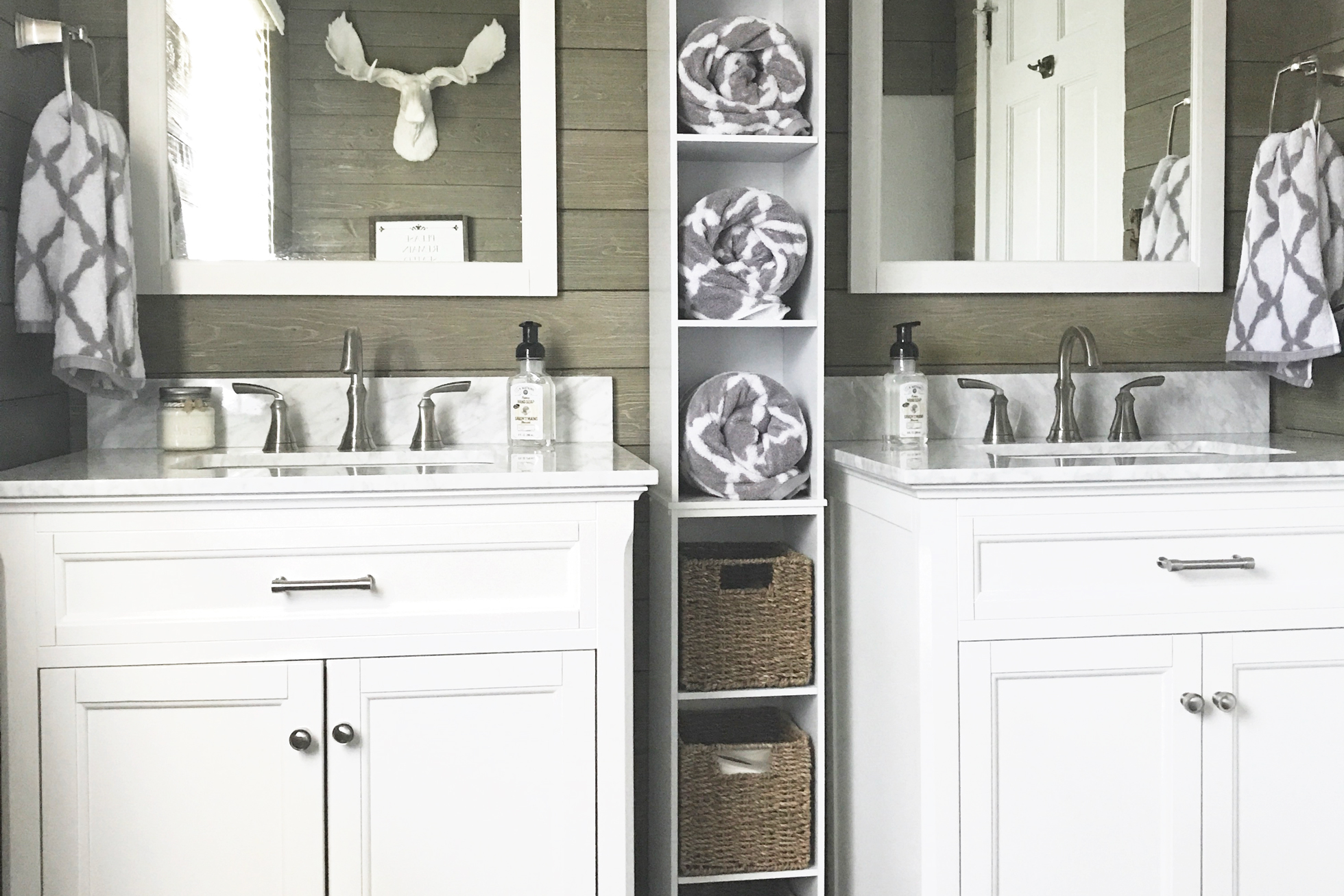 Two sinks in a shiplap bathroom with shelving between