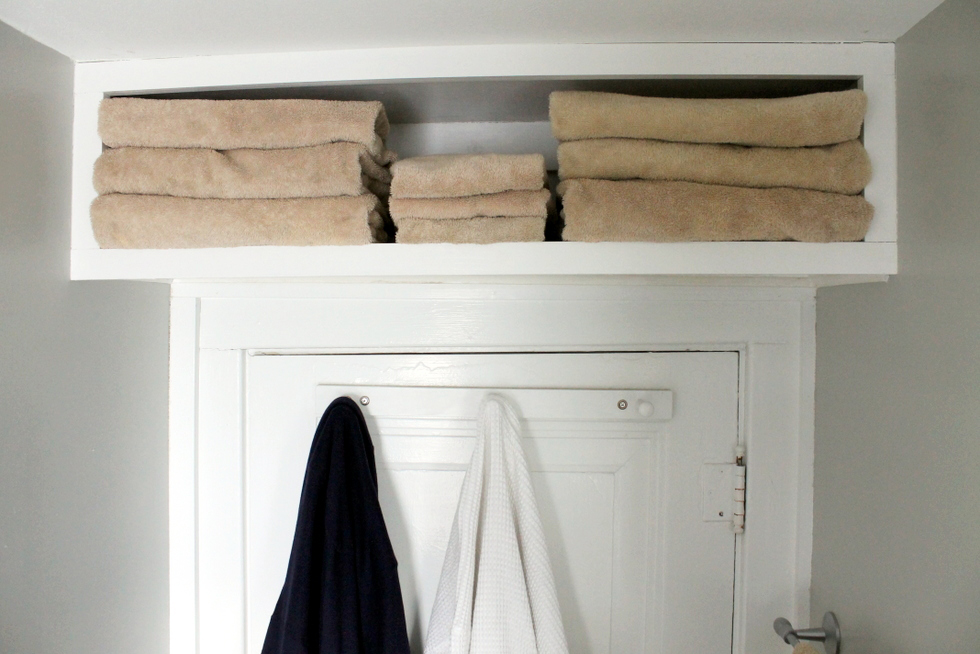 Above-the-door shelf filled with towels in bathroom