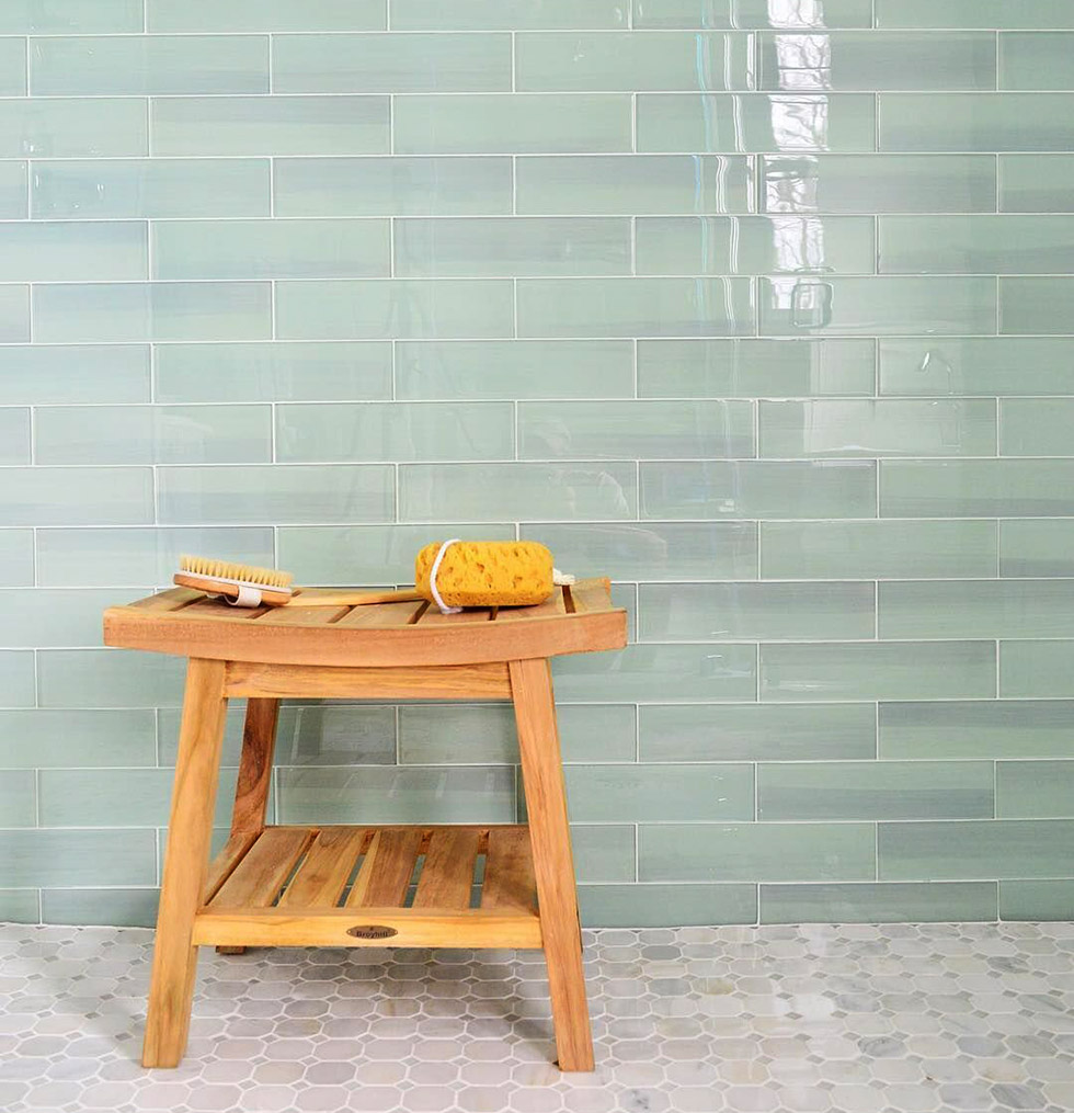 Natural wood bathroom stool before wall of green glass tiles