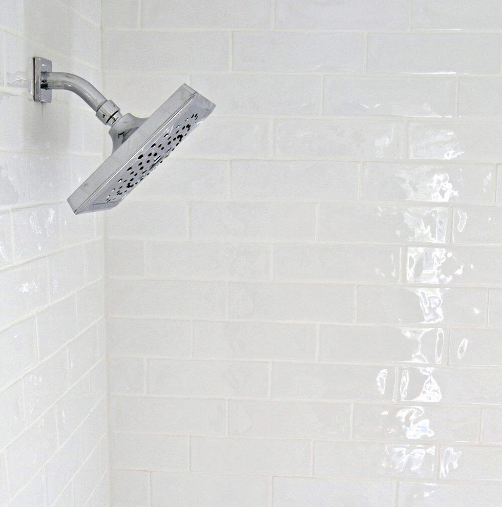 Silver shower head against white wall of subway tile