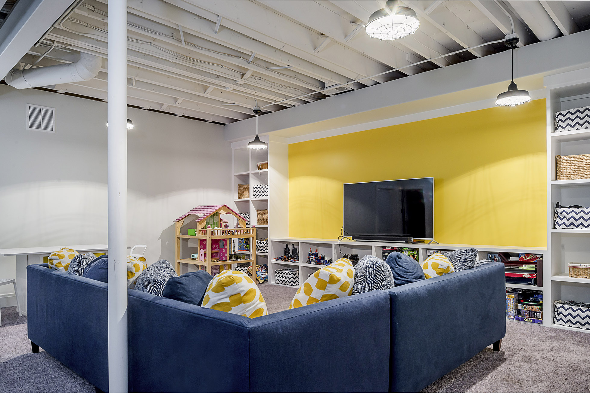 Blue and yellow basement with built-in shelves, open ceiling