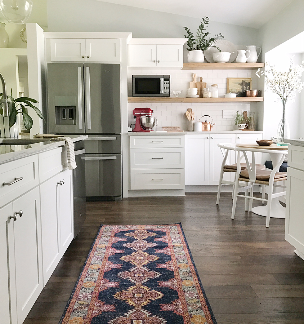 All-white kitchen with dark wood floors and red and blue rug